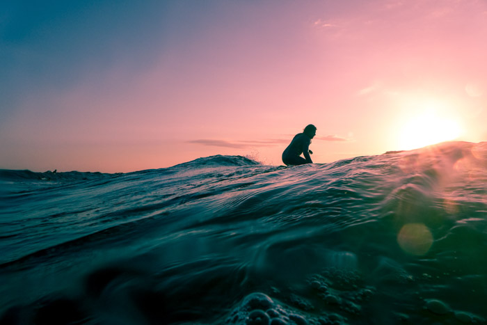 A dreamy adventure photography shot of a girl on the ocean at sunset 