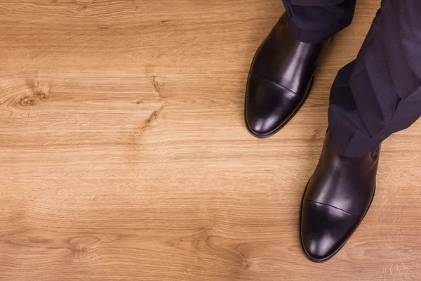 Legs of businessman on parquet, top view Stock Image