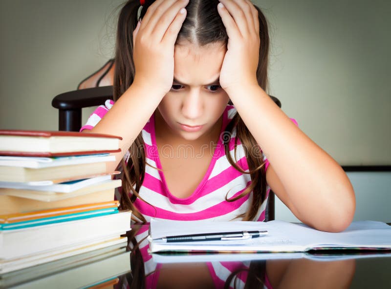 Angry and tired schoolgirl studying stock images