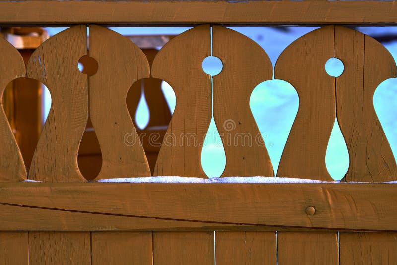 Background - decorative wooden painted fence. Close-up. Winter sunny evening royalty free stock photo