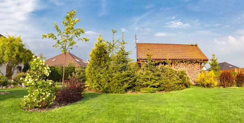 Backyard of a family house. Landscaped garden with green mown grass, wood shelter. Backyard of a family house. Landscaped garden green mown grass, plants and stock image