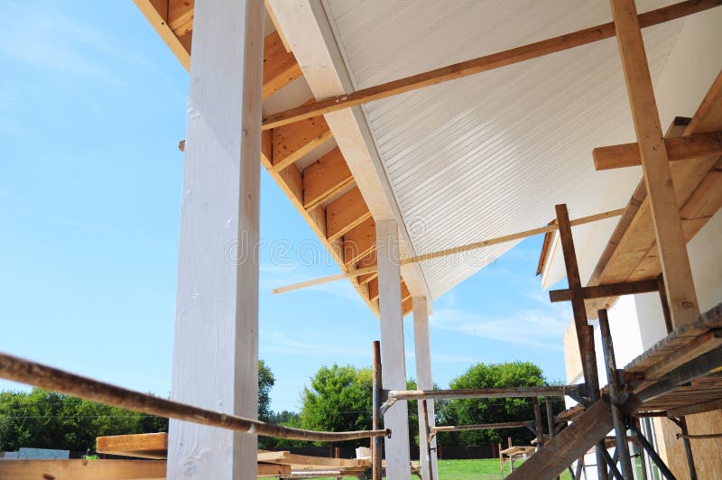 Building house patio roofing with wooden pillars and unfinished soffits and fascia boards installation. Building house roofing with wooden pillars and royalty free stock photo