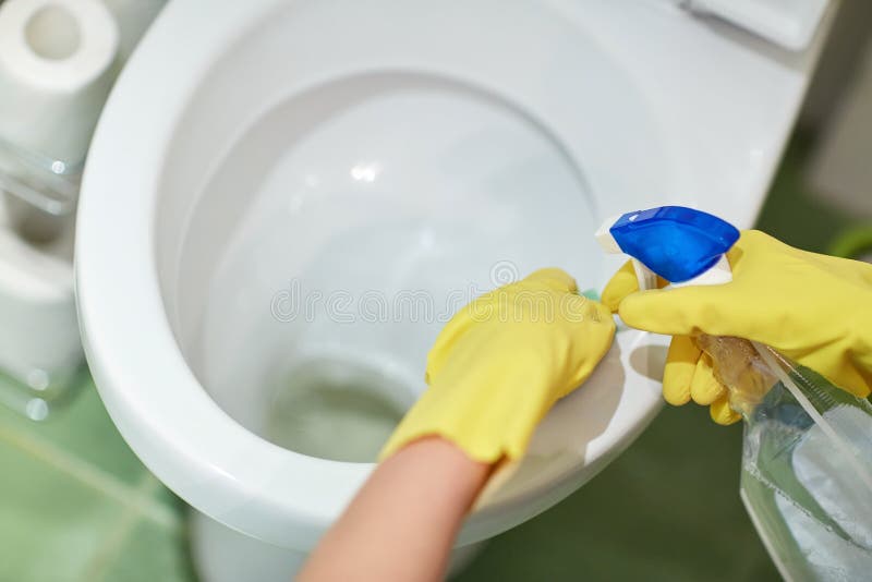 Close up of hand with detergent cleaning toilet. People, housework and housekeeping concept - close up of hand in rubber glove with detergent cleaning toilet pan stock image