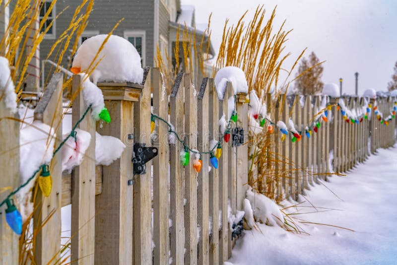 Colorful lights on snowy wooden gate and fence stock photo