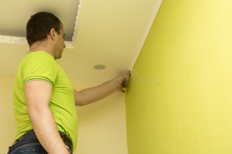 Constructor installs plastic molding to ceiling and wall royalty free stock photography