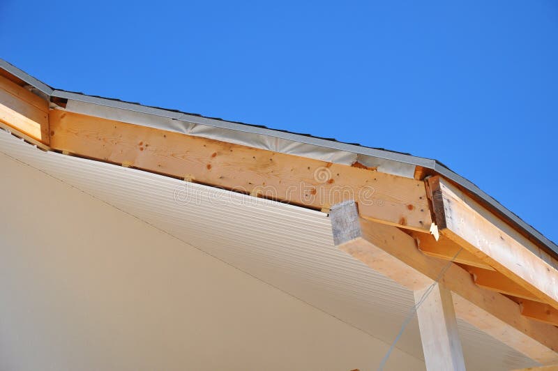 Corner of house with eaves, wooden beams. Install soffits. Against blue sky stock images