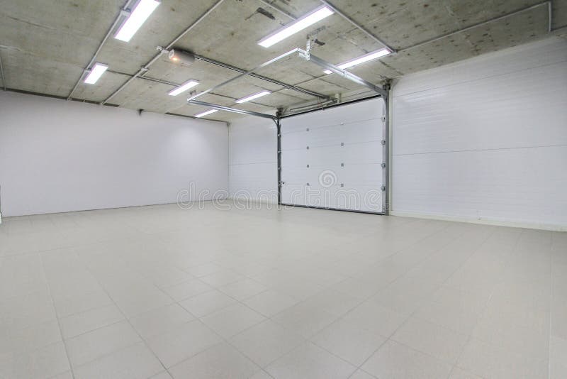 Empty parking garage, warehouse interior with large white gates and gray tile floor royalty free stock image