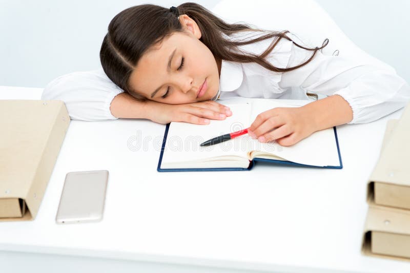 Fall asleep on lesson. Girl child fall asleep while reading book table white background. Schoolgirl tired of studying. And reading book. Kid girl school uniform royalty free stock photo