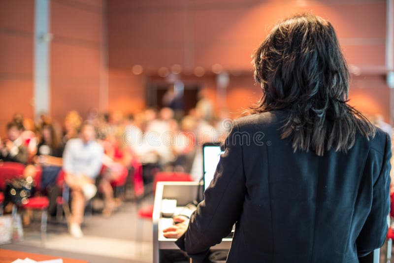 Female public speaker giving talk at Business Event. stock photo