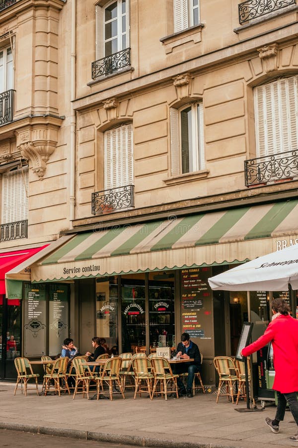 French cafe terrace. Paris, France - April 6, 2019: Charming traditional french cafe with tables on terrace in evening, landmark in Paris royalty free stock image