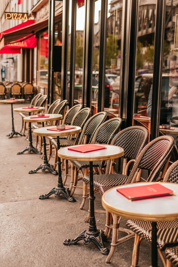 French cafe terrace. Paris, France - April 6, 2019: Charming traditional french cafe with tables on terrace in evening, landmark in Paris royalty free stock image