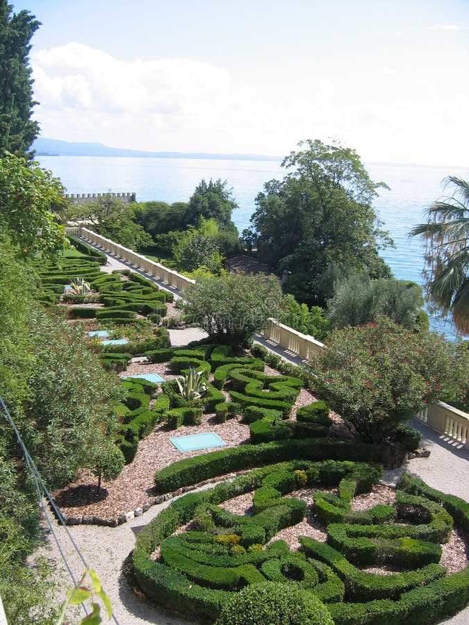 French garden in terrace on the lake of Garda in Italy. Travel destination. Blue lake. Blue sky with clouds. Sunny day. Multiform of trees. Differente kind of royalty free stock images