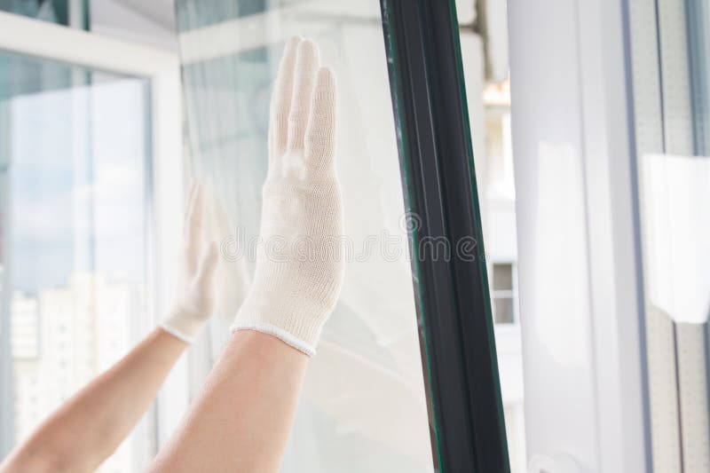 Gloved hands of a craftsman install glass in a plastic window frame stock images