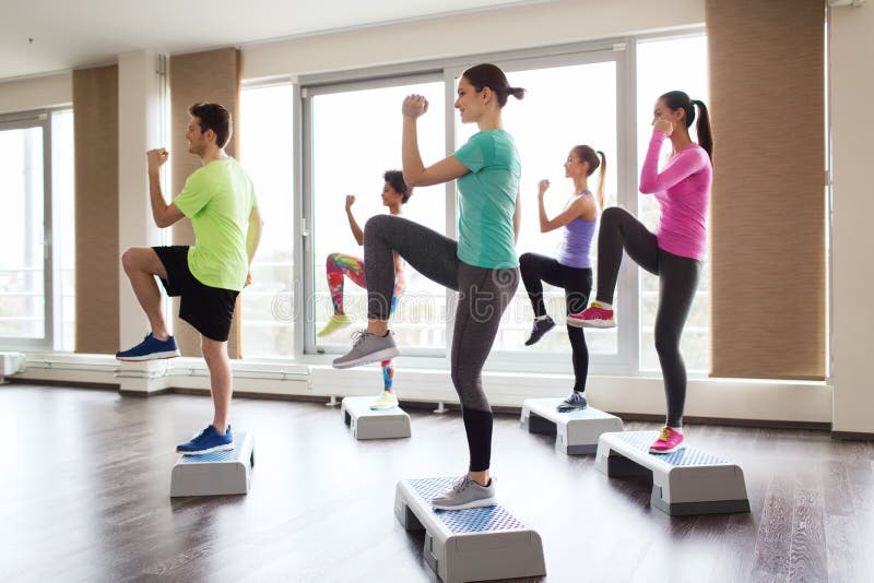 Group of people working out with steppers in gym stock photo