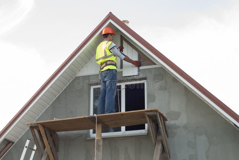 Installation of soffits. Construction worker mounts a soffit on the roof eaves royalty free stock photo