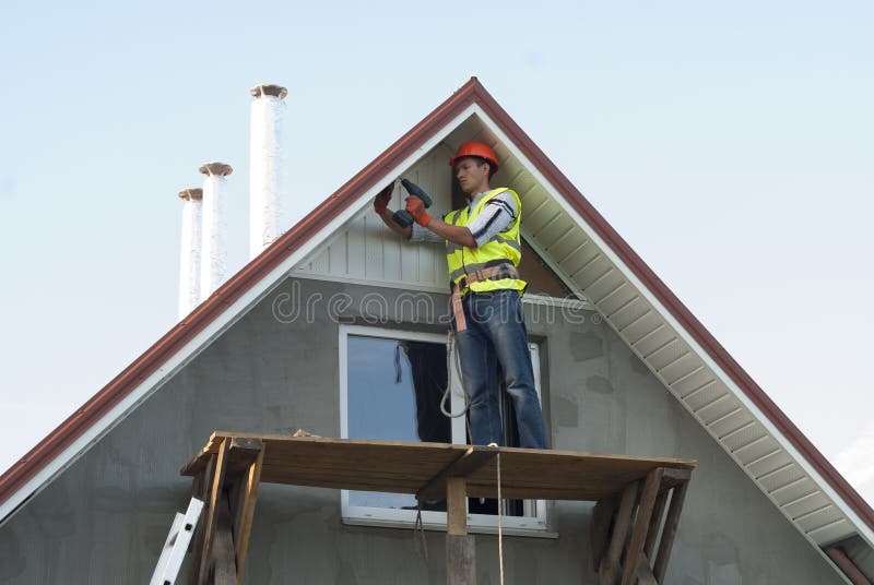Installation of soffits. Construction worker mounts a soffit on the roof eaves royalty free stock photography