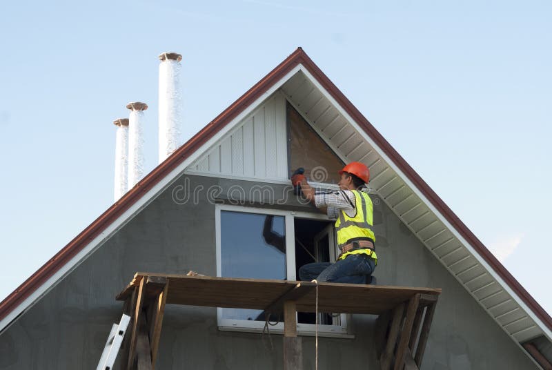 Installation of soffits. Construction worker mounts a soffit on the roof eaves royalty free stock photos