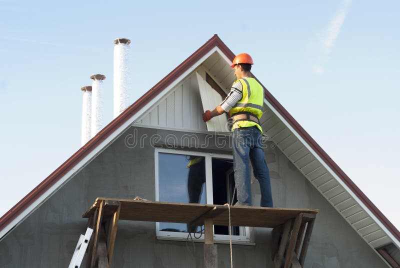 Installation of soffits. Construction worker mounts a soffit on the roof eaves stock photo