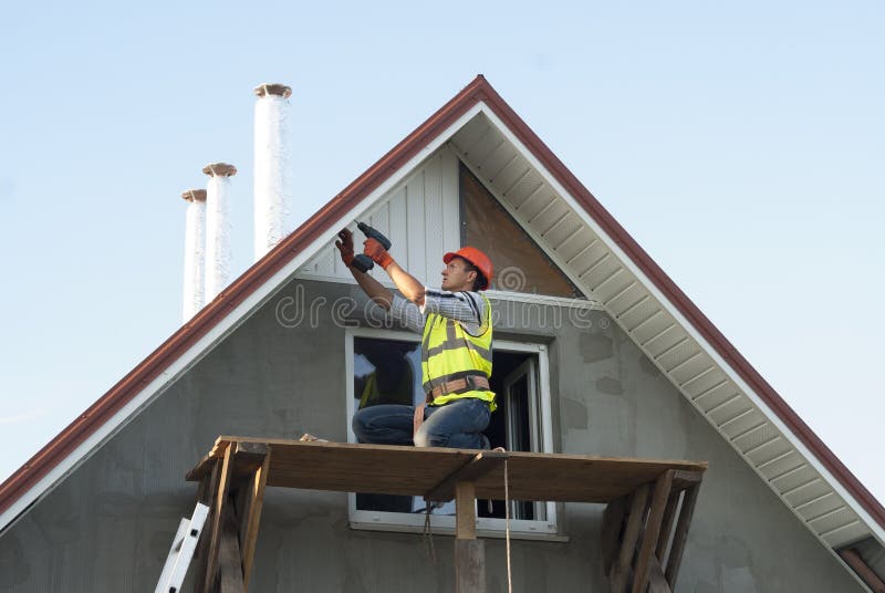 Installation of soffits. Construction worker mounts a soffit on the roof eaves stock photography