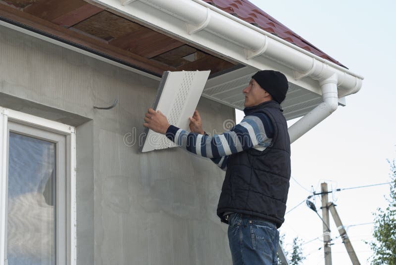 Installation of soffits. Construction worker mounts a soffit on the roof eaves royalty free stock photo