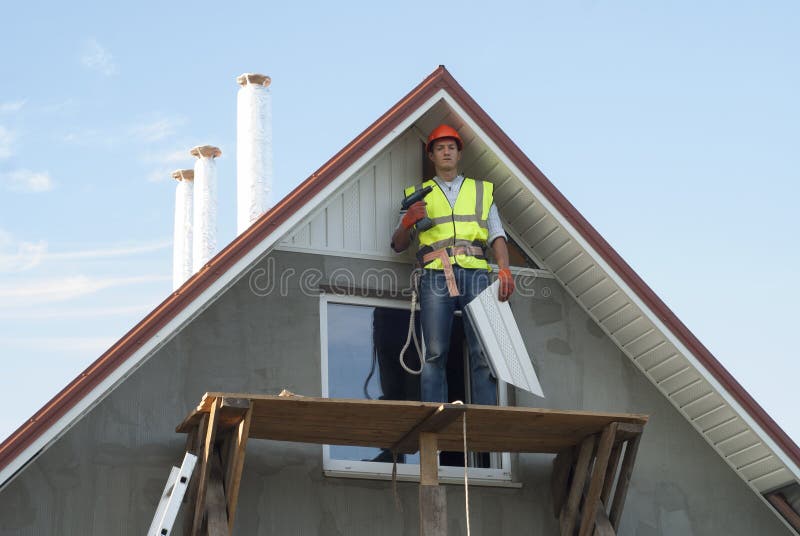 Installation of soffits. Construction worker mounts a soffit on the roof eaves stock images