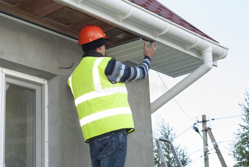 Installation of soffits. Construction worker mounts a soffit on the roof eaves royalty free stock photography