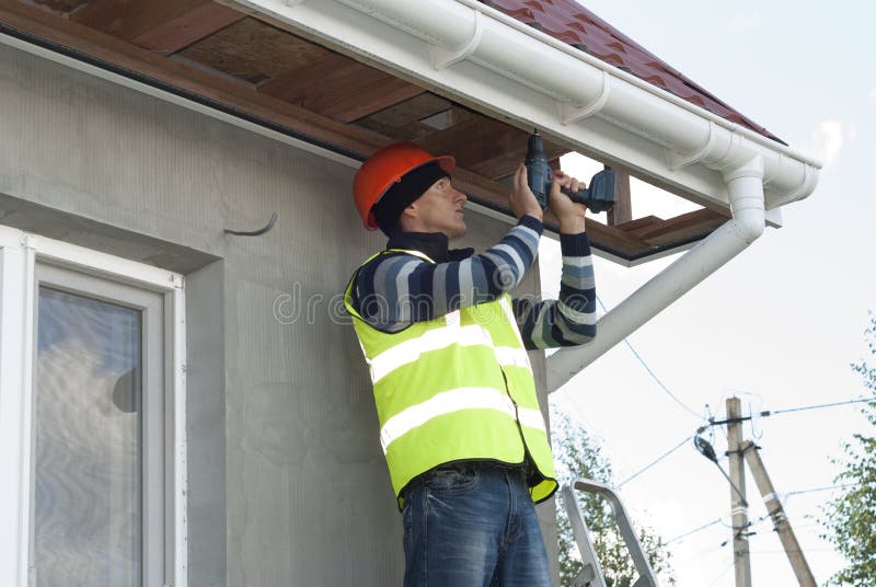 Installation of soffits. Construction worker mounts a soffit on the roof eaves royalty free stock photos