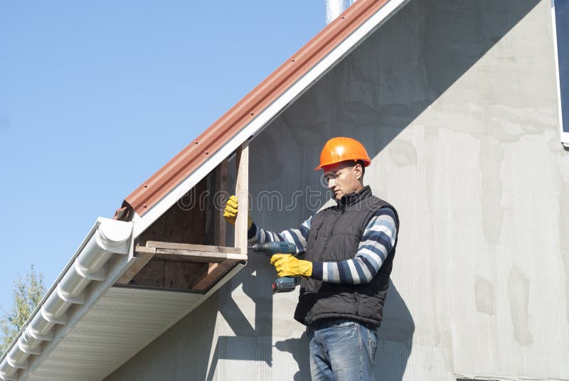 Installation of soffits. Construction worker mounts a soffit on the roof eaves stock photos