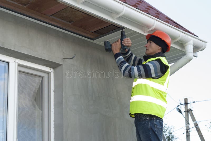 Installation of soffits. Construction worker mounts a soffit on the roof eaves royalty free stock images