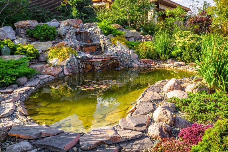 Landscape design of home garden close-up. Beautiful landscaping with small pond and waterfall. Landscaped place with rocks at country house. Stone landscaping royalty free stock photography