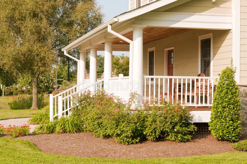 Landscaped house porch. A modest suburban house with a large white porch and landscaping stock photography