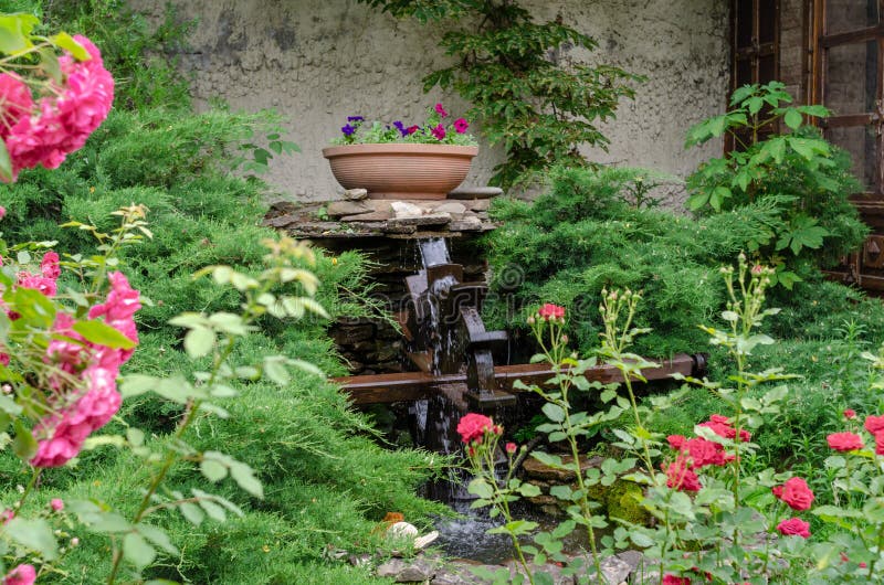 Landscaping in the courtyard of a private house, decorative fountain, water pours into the wheel. Landscaping in the courtyard of a private house, decorative royalty free stock photography