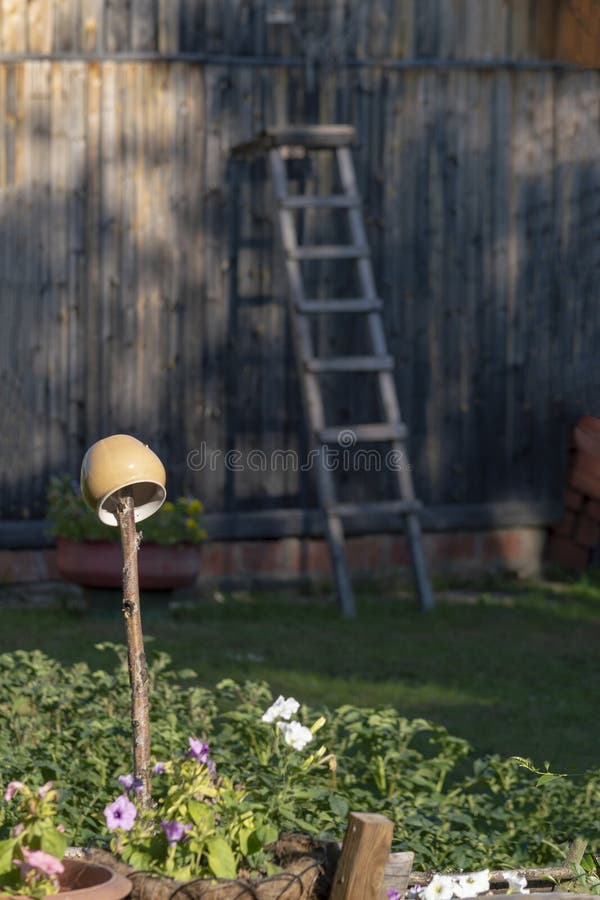 The main pot dries on a stick in the courtyard of a private house in Siberia, and in the background is a wooden staircase. Yard summer.  Front view royalty free stock photography
