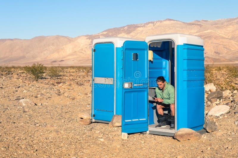 Man sitting in the Toilet in the middle of the desert - Death Va. Man sitting in the Toilet in the middle of the desert in Death Valley California stock photo