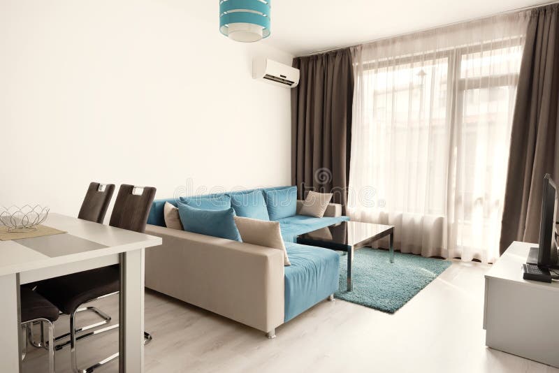 Modern bright and cozy living room interior design with sofa, dining table and kitchen. Grey and turquoise blue studio apartment stock images