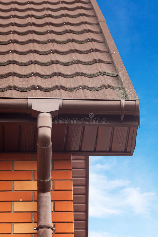 New white rain gutter on a roof with Drainage System, Stone Coated Metal tile, Plastic Siding Soffits and Eaves. New white rain gutter on a roof with Drainage royalty free stock images