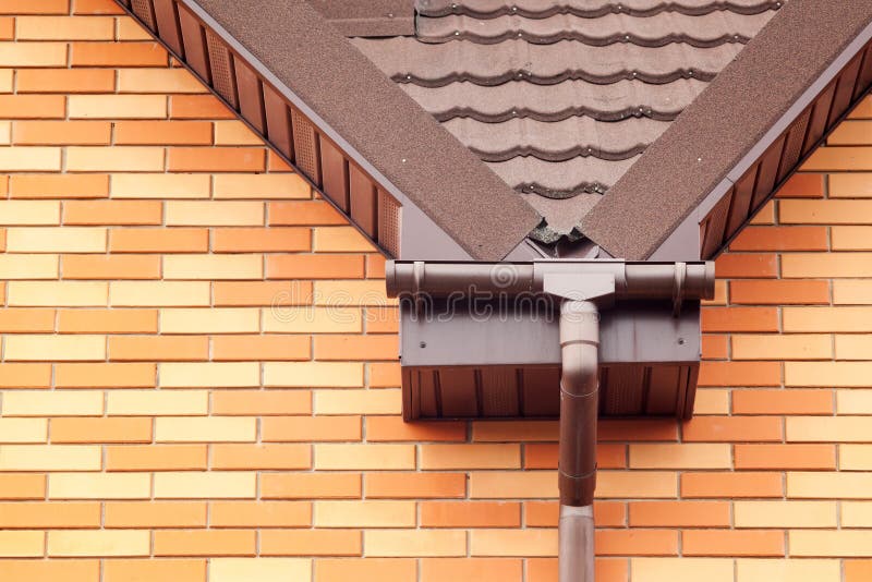 New white rain gutter on a roof with Drainage System, Stone Coated Metal tile, Plastic Siding Soffits and Eaves. New white rain gutter on a roof with Drainage royalty free stock image