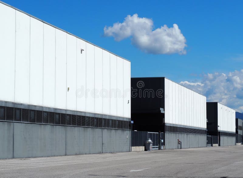 A row of large black and white industrial warehouse buildings with the road in front . royalty free stock photography