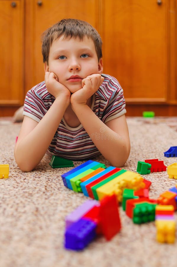 Sad child near the fallen tower from the constructor stock images
