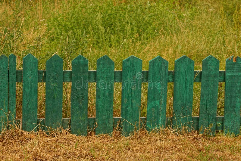 Small green decorative wooden fence in tall grass stock photo