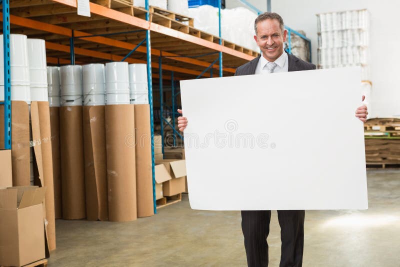 Smiling warehouse manager holding large white poster stock images