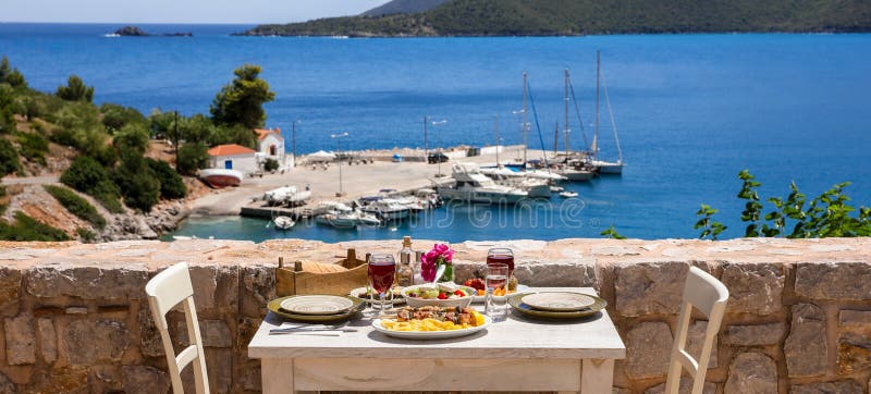 A table served for two with chicken souvlaki and french fries, greek salad, snacks and drinks on the summer terrace of the hotel r. A table served for two with royalty free stock photo