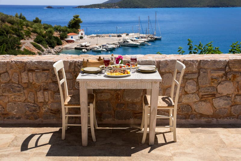 A table served for two with chicken souvlaki and french fries, greek salad, snacks and drinks on the summer terrace of the hotel r. A table served for two with royalty free stock photography