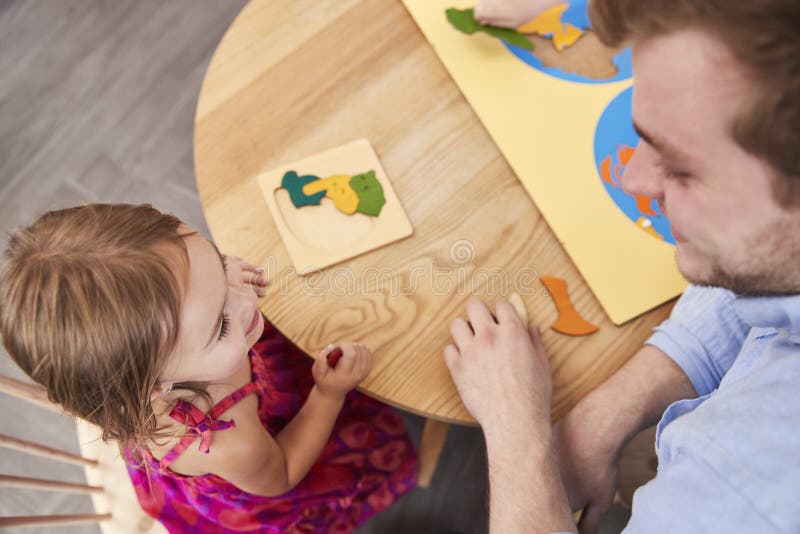 Teacher And Pupil Using Wooden Shapes In Montessori School stock photography