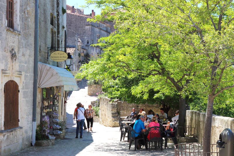 Terrace and soapshop in Les Baux-de-Provence, France. Relaxing people at terrace and a touristic soap shop in a sunny village of Baux de Provence, France, a royalty free stock photography