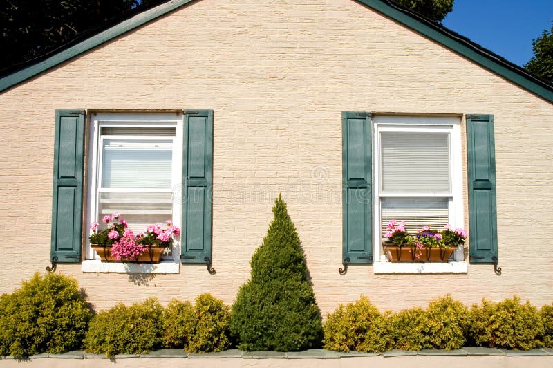 Tiny cottage with flower boxes. The front side of a small but neat cottage or bungalow with nice landscaping and pretty window flower boxes royalty free stock images
