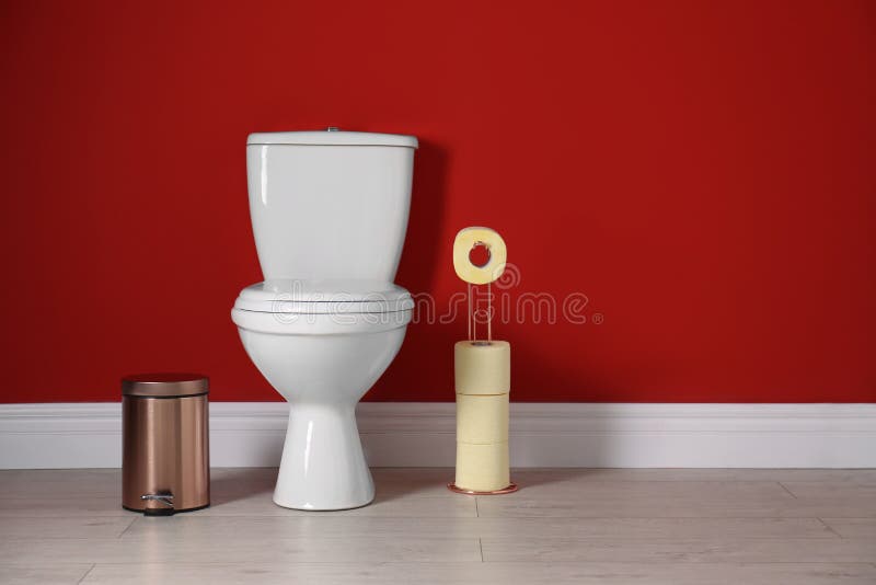 Toilet bowl with paper rolls and trash bin in restroom. Space for text stock image