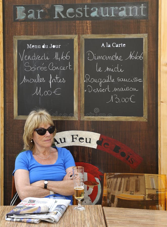 Tourist at a French cafe terrace. Tourist drinking a beer and reading a newspaper at a French cafe terrace stock photography