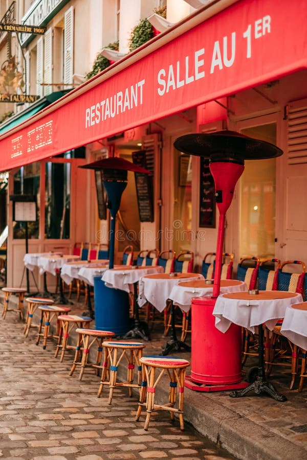 Traditional french cafe with tables on terrace. Paris, France - April 6, 2019: Charming traditional french cafe with tables on terrace in evening, landmark in royalty free stock photo