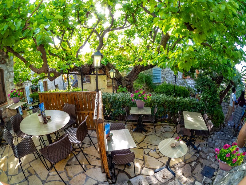 Historic restaurant terrace in Eze village, France. Traditional restaurant terrace inside Eze village with tables and chairs among vintage house architecture, in royalty free stock photos